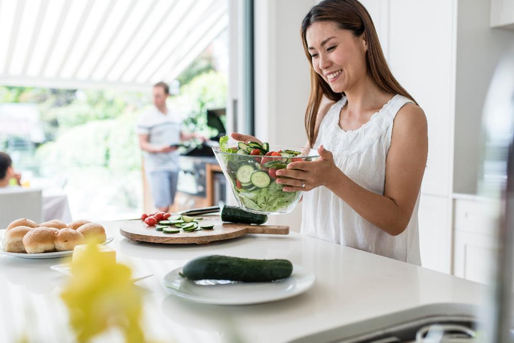 woman making a salad in kitchen | dental bonding los gatos ca