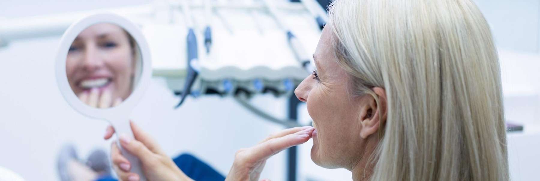 woman holding mirror smiling | los gatos ca dentist