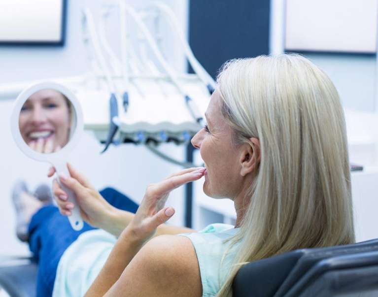blonde woman smiling in mirror | dentist los gatos ca