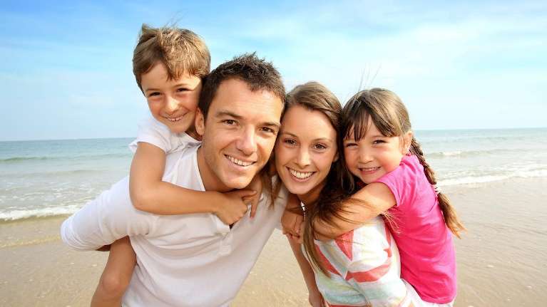 family of four smiling on beach | dentist los gatos ca