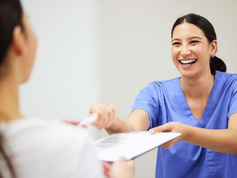 dental assistant handing patient paperwork | los gatos cosmetic dentist