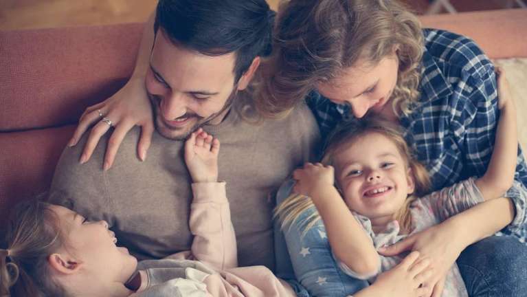 Mother, father, and two young daugters embracing and smiling in los gatos ca